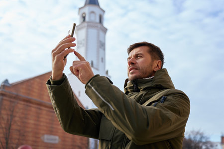 Man holding smartphone and taking photo of tower outdoorsの写真素材