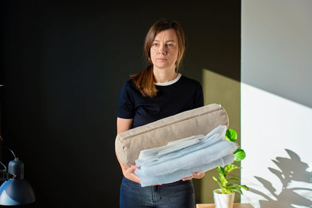 Woman standing and holding pillow cover with textile stuffing. Concept of handmade cushion productionの写真素材