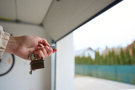 Hand holding keys near open garage door. Concept of home ownership