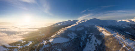 Aerial shot of majestic sunrise in the mountains. Valley between the mountains is covered with fog...