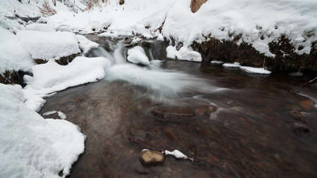 Winter mountain waterfall snow scene. Snowy mountain waterfall landscape. Winter mountain waterfall in Shipot waterfall - Carpathian Mountains, Ukraine.の写真素材