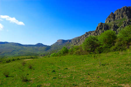 Horizontal background with a magnificent landscape of the Crimean Peninsula. Top view of the mountains covered with lush greenery and the thick clouds below the peaks. Clear blue sky. Copy space.の写真素材
