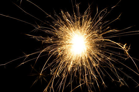 fire sparks particles on black background for overlay design, shot taken with slow shutter, long traces, large sheaf of sparks, emission source on the top left cornerの写真素材