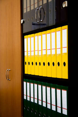 row of folders for papers and documentation on a shelf in the officeの写真素材
