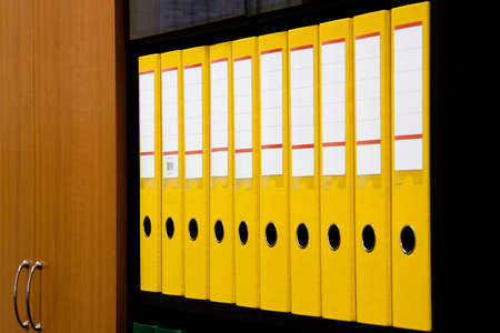 row of folders for papers and documentation on a shelf in the officeの写真素材