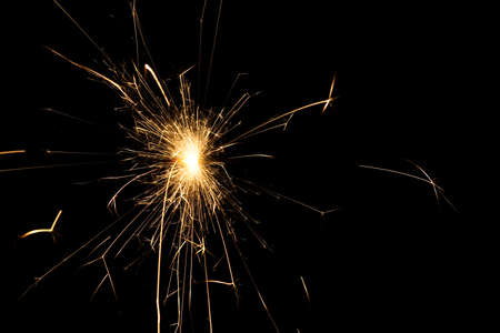 fire sparks particles on black background for overlay design, shot taken with slow shutter, long traces, large sheaf of sparks, emission source on the top left cornerの写真素材