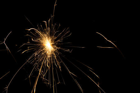 fire sparks particles on black background for overlay design, shot taken with slow shutter, long traces, large sheaf of sparks, emission source on the top left cornerの写真素材