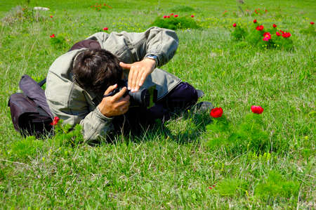 Man taking photographs of red flowers in a spring gardenの写真素材