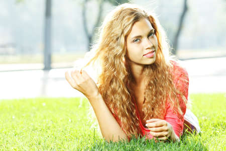 Photo of cute blond female laying down on chamomile field and looking up in sky, sunny day, warm weather, spring holiday and vacation, pretty woman enjoying beautiful nature, daisy fieldの写真素材