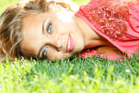 Photo of cute blond female laying down on chamomile field and looking up in sky, sunny day, warm weather, spring holiday and vacation, pretty woman enjoying beautiful nature, daisy fieldの写真素材