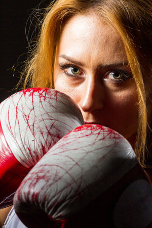 Muscular young athletic sportswoman in sportswear with bands or gloves in the gym on a dark background. Sports martial arts. Copy space for ads for fitness nutrition, sports equipment or exercise.の写真素材