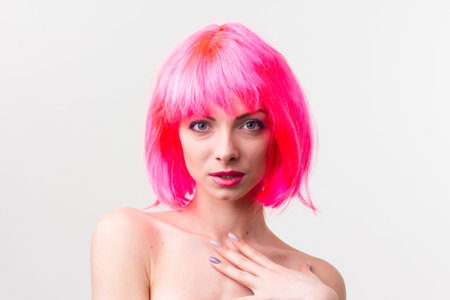Image of excited beautiful woman in wig laughing while posing with candy isolated over pink backgroundの写真素材