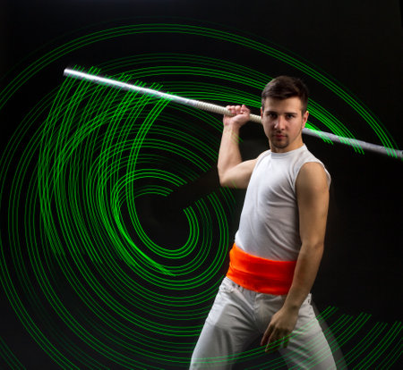 Light trail. Shooting with combined lighting. Young professional athlete plays with lighting equipment on a black background in mixed light. Working out in motion, action. Strength and energy.の写真素材