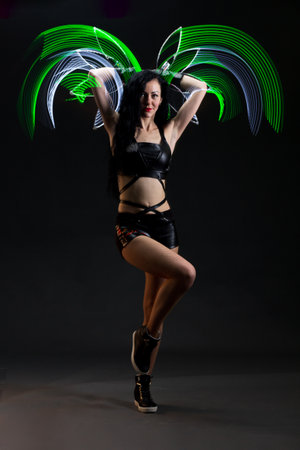 Light trail. Shooting with combined lighting. Young professional athlete plays with lighting equipment on a black background in mixed light. Working out in motion, action. Strength and energy.の写真素材