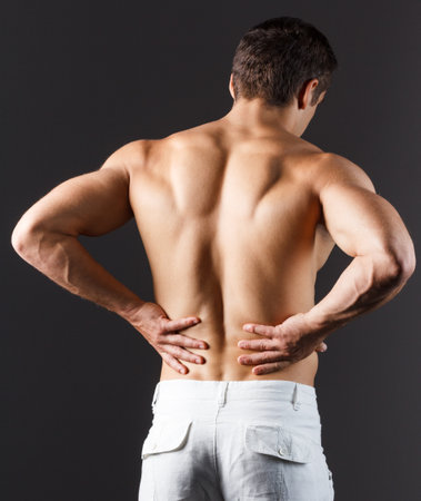 pain relief, sport, bodybuilding, strength and people concept - young man standing over black backgroundの写真素材