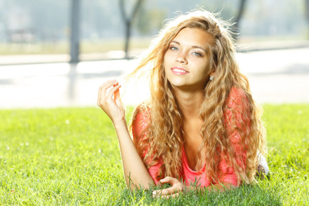 Photo of cute blond female laying down on chamomile field and looking up in sky, sunny day, warm weather, spring holiday and vacation, pretty woman enjoying beautiful nature, daisy fieldの写真素材