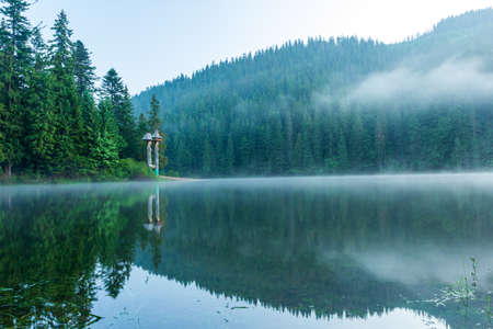Beautiful nature and a wonderful landscape with lush green forests and vegetation around the pearl of the Carpathians - Lake Synevyr. Carpathians in Ukraine. Mystical fog over the great firs.の写真素材