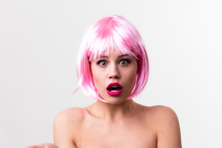 Face of a young woman with bright makeup on a pink background with gathered hair in a smooth ponytail.の写真素材