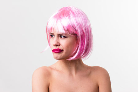 Face of a young woman with bright makeup on a pink background with gathered hair in a smooth ponytail.の写真素材