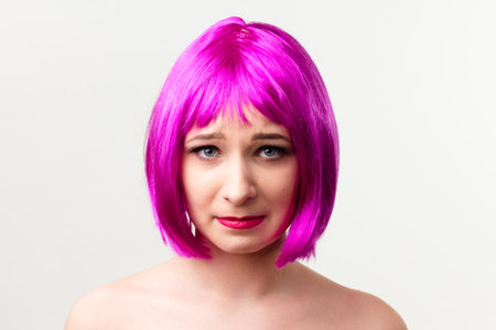 Face of a young woman with bright makeup on a pink background with gathered hair in a smooth ponytail.の写真素材