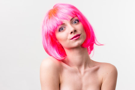 Image of excited beautiful woman in wig laughing while posing with candy isolated over pink backgroundの写真素材