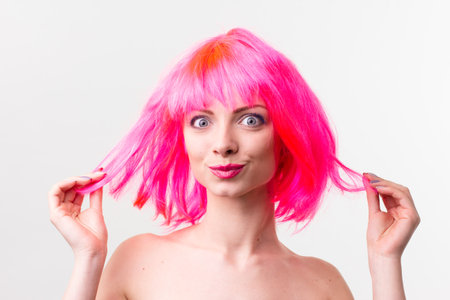 Image of excited beautiful woman in wig laughing while posing with candy isolated over pink backgroundの写真素材