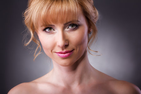 Beautiful woman face close up portrait young studio on grayの写真素材