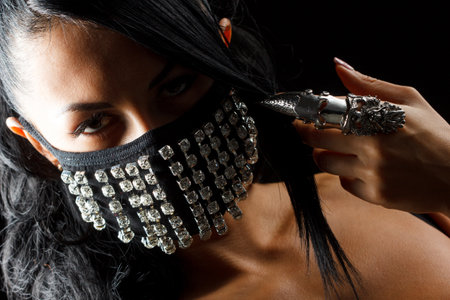 close-up portrait of beautiful brunette woman with facial body art hiding half of her face with maskの写真素材