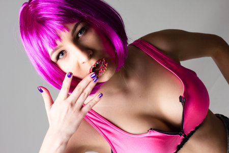 Face of a young woman with bright makeup on a pink background with gathered hair in a smooth ponytail.の写真素材