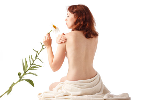 Happy pregnant woman in the studio on the background of a white wall. Smiling, looking at the camera, holding a beautiful flower. Getting positive emotions with the help of herbal medicineの写真素材