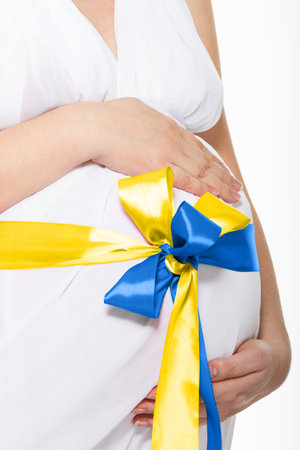 The War in Ukraine, Ukrainian conflict background. The Ukrainian flag is painting on the belly of a pregnant woman.の写真素材