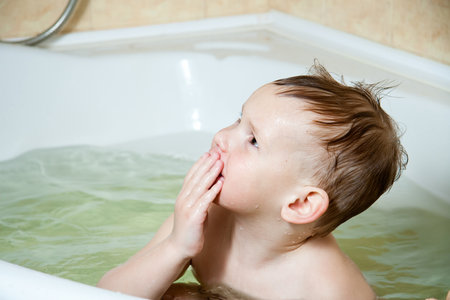 Happy child, little girl, bathes in a bubble bath, washes her face. The concept of childrens hygiene, joy, splashes, laughter, have fun. Family lifestyle.の写真素材