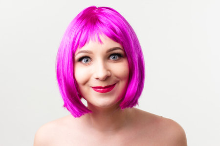 Face of a young woman with bright makeup on a pink background with gathered hair in a smooth ponytail.の写真素材