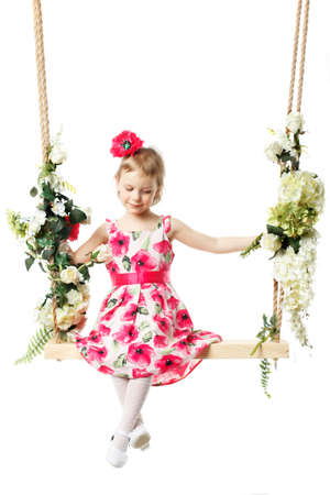 Beautiful little girl swinging on a swing. The concept of family happiness, summer holidays. Isolated on white background.の写真素材