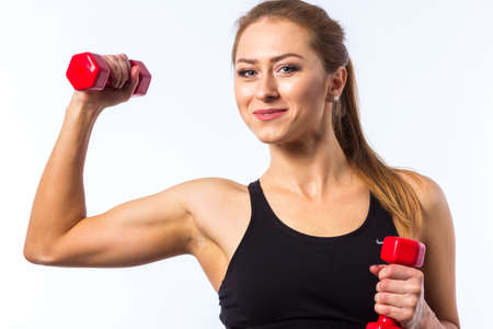 Beautiful young caucasian fitness woman working out with hand weights, arms outstretched building strength.の写真素材