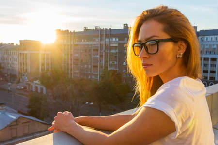 Happy smiling girl wearing purple sunglasses, yellow turtleneck, golden wrist watch, hoop earrings posing in street. Autumn fashion, advertising concept. Copy, empty space for textの写真素材