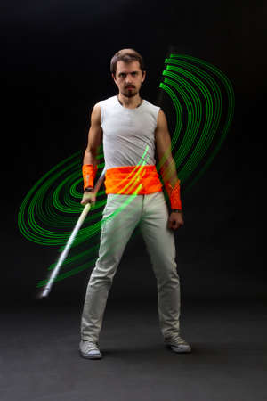 Light trail. Shooting with combined lighting. Young professional athlete plays with lighting equipment on a black background in mixed light. Working out in motion, action. Strength and energy.の写真素材