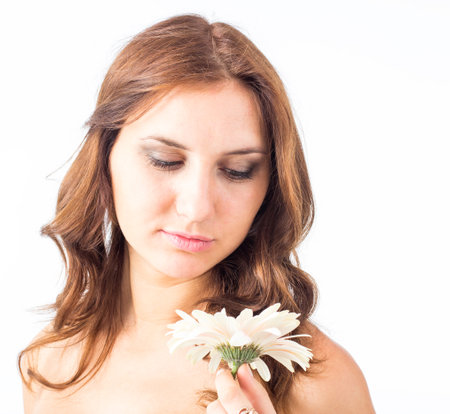 Portrait of beautiful woman with bright make up holding pink daisy in handsの写真素材