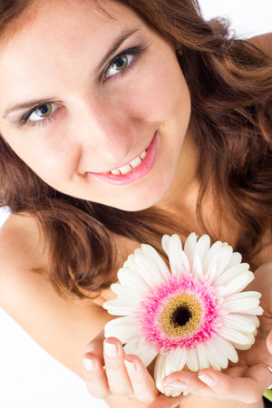 Portrait of beautiful woman with bright make up holding pink daisy in handsの写真素材