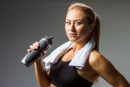 Taking refreshment. A young blond woman drinking water after a hard workout.の写真素材