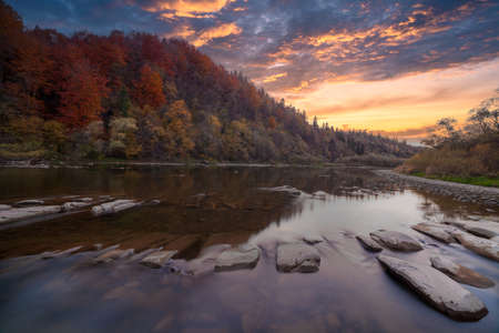 View of the waterfall in autumn. Waterfall in autumn colors. Mountain river in the autumn landscape....
