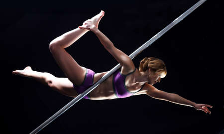 The strong and graceful young girl performing acrobatic exercises on pylon