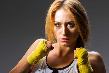 Muscular young athletic sportswoman in sportswear with bands or gloves in the gym on a dark background. Sports martial arts. Copy space for ads for fitness nutrition, sports equipment or exercise.の写真素材