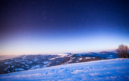 Fog moving over the mountain in winter with a star-shaped skyの写真素材