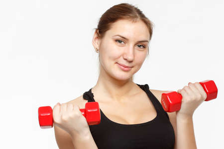 Female fitness model excercising in studio with dunbell weights and doing a floor routine of stretches and lifts on a matt.の写真素材