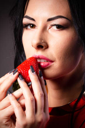 Portrait of a brunette beauty with honey dripping strawberry.の写真素材