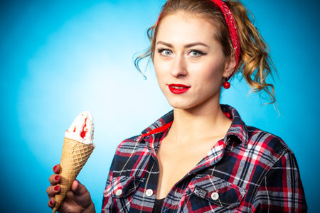 Beautiful pin up stylized young pregnant woman in kitchen drinking juiceの写真素材