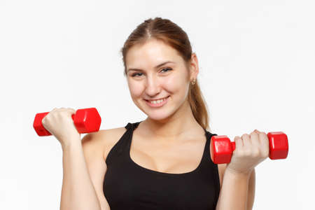 Female fitness model excercising in studio with dunbell weights and doing a floor routine of stretches and lifts on a matt.の写真素材