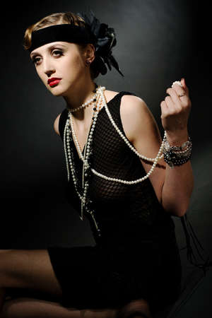 Portrait of a glamorous dark haired model with perfect makeup wearing a luxurious necklace, black...