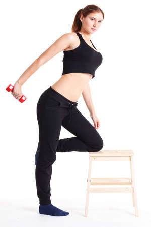 Female fitness model excercising in studio with dunbell weights and doing a floor routine of stretches and lifts on a matt.の写真素材
